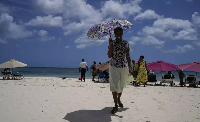 A woman walks off the beach after attending a religious gathering in Bridgetown, Barbados, Sunday, June 30, 2024. Hurricane Beryl strengthened into a Category 4 storm as it approaches the southeast Caribbean. (AP Photo/Ramon Espinosa)