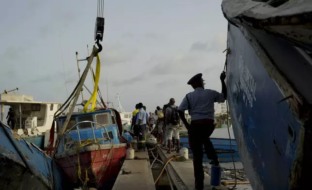 Fishermen fix up a boat damaged by Hurricane Beryl to be lifted from the Bridgetown Fisheries, Barbados, Tuesday, July 2, 2024. (AP Photo/Ricardo Mazalan)