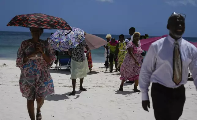 People walk off the beach after attending a religious gathering in Bridgetown, Barbados, Sunday, June 30, 2024. Hurricane Beryl strengthened into a Category 4 storm as it approaches the southeast Caribbean. (AP Photo/Ramon Espinosa)