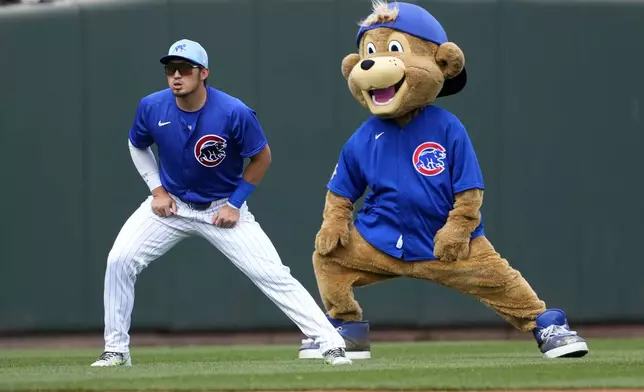 FILE. The Chicago Cubs mascot playfully stretches with Seiya Suzuki prior to a spring training baseball game against the Los Angeles Angels, Wednesday, March 6, 2024, in Mesa, Ariz. Stretching can help make you more flexible, improve range of motion in your joints — and feel good. (AP Photo/Matt York, File)