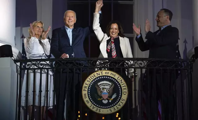 First lady Jill Biden and second gentleman Douglass Emhoff watch as President Joe Biden raises the hand of Vice President Kamala Harris as they view the Independence Day firework display over the National Mall from the balcony of the White House, Thursday, July 4, 2024, in Washington. (AP Photo/Evan Vucci)