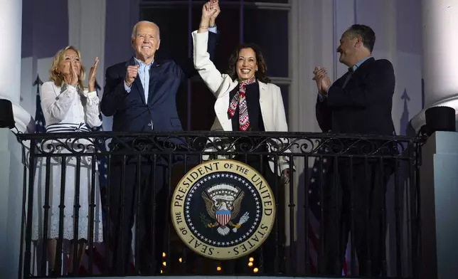 First lady Jill Biden and second gentleman Douglass Emhoff watch as President Joe Biden raises the hand of Vice President Kamala Harris while they view the Independence Day firework display over the National Mall from the balcony of the White House, Thursday, July 4, 2024, in Washington. (AP Photo/Evan Vucci)