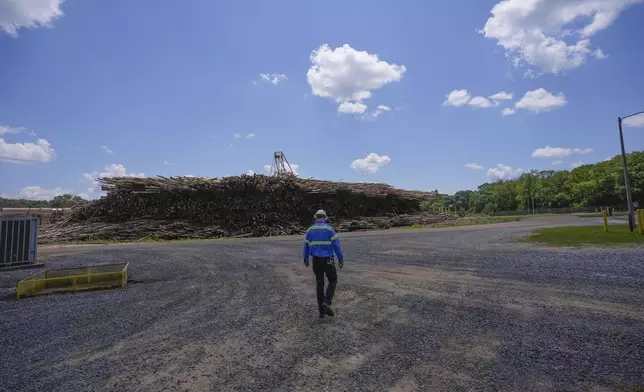 An employee walks toward a pile of lumber to be used during a tour of a Drax facility in Gloster, Miss., Monday, May 20, 2024. Wood pellet production skyrocketed across the U.S. South to feed the European Union's push this past decade for renewable energy to replace fossil fuels like coal. (AP Photo/Gerald Herbert)