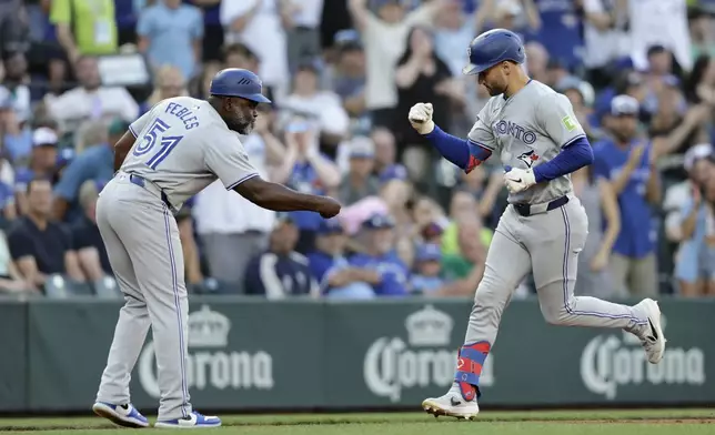 Toronto Blue Jays' Kevin Kiermaier, right, is congratulated by third base coach Carlos Febles, left, after hitting a solo home run on a pitch from Seattle Mariners starter Luis Castillo during a baseball game, Friday, July 5, 2024, in Seattle. (AP Photo/John Froschauer)