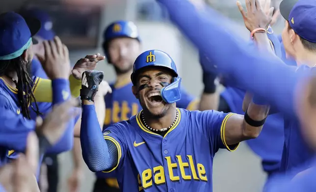 Seattle Mariners' Julio Rodriguez celebrates in the dugout after scoring against the Toronto Blue Jays in a baseball game, Friday, July 5, 2024, in Seattle. (AP Photo/John Froschauer)