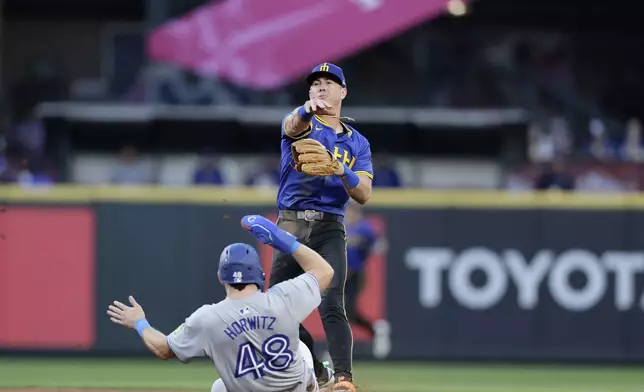 Toronto Blue Jays' Spencer Horwitz (48) is forced out at second as Seattle Mariners second baseman Dylan Moore, top, throws to first to complete a double play against Blue Jays' Bo Bichette during the sixth inning in a baseball game, Friday, July 5, 2024, in Seattle. (AP Photo/John Froschauer)