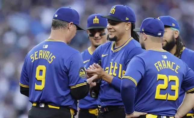 Seattle Mariners starting pitcher Luis Castillo, denter, smiles at manager Scott Servais (9) who asks for the ball to replace him during the seventh inning against the Toronto Blue Jays in a baseball game, Friday, July 5, 2024, in Seattle. (AP Photo/John Froschauer)