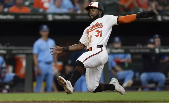 Baltimore Orioles' Cedric Mullins (31) prepares to slide into home plate to score on an RBI single hit in by Ramon Urias during the fourth inning of a baseball game against the Toronto Blue Jays, Tuesday, July 30, 2024, in Baltimore. (AP Photo/Stephanie Scarbrough)