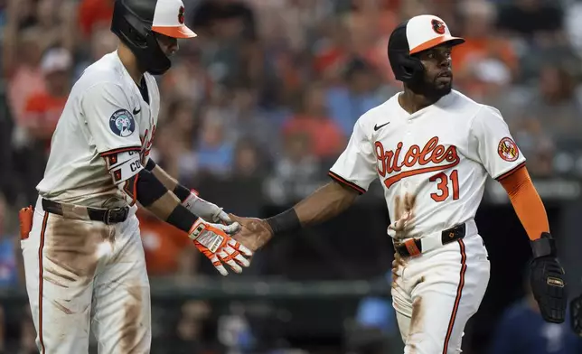 Baltimore Orioles' Cedric Mullins (31) celebrates with Colton Cowser, left, after scoring on an RBI single hit in by Ramon Urias during the fourth inning of a baseball game against the Toronto Blue Jays, Tuesday, July 30, 2024, in Baltimore. (AP Photo/Stephanie Scarbrough)