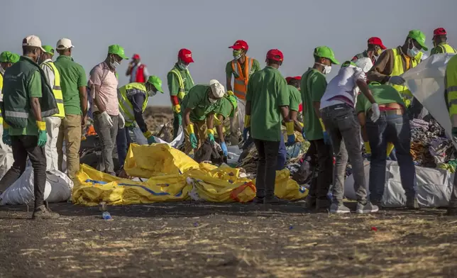 FILE - Workers collect debris on March 12, 2019 at the scene where an Ethiopian Airlines Boeing 737 Max 8 crashed shortly after takeoff, killing all 157 on board, near Bishoftu, or Debre Zeit, south of Addis Ababa, in Ethiopia. On Sunday, July 7, 2024, the Justice Department said Boeing has agreed to plead guilty to a criminal fraud charge stemming from two deadly crashes of 737 Max jetliners. (AP Photo/Mulugeta Ayene, File)