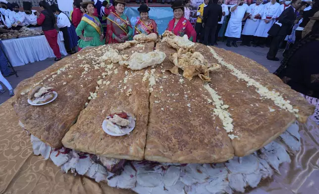 Cholitas pose for a photo during the presentation of a giant "sandwich de chola", in La Paz, Bolivia, Tuesday, July 2, 2024. Gastronomy experts and student chefs prepared the traditional Bolivian roasted pork sandwich in hopes of breaking the world's record for largest sandwich. (AP Photo/Juan Karita)