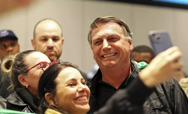 Brazilian former President Jair Bolsonaro poses for a photo with supporters after arriving at the international airport in Florianopolis, Santa Catarina state, Brazil, Friday, July 5, 2024. Brazilian police have indicted Bolsonaro for money laundering and criminal association in connection with undeclared diamonds the far-right leader received from Saudi Arabia during his time in office, according to a source with knowledge of the accusations. (AP Photo/Heuler Andrey)