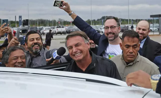 Former Brazilian President Jair Bolsonaro smiles as he prepares to depart the international airport in Florianopolis, Santa Catarina state, Brazil, Friday, July 5, 2024. Brazilian police have indicted Bolsonaro for money laundering and criminal association in connection with undeclared diamonds the far-right leader received from Saudi Arabia during his time in office, according to a source with knowledge of the accusations. (AP Photo/Heuler Andrey)