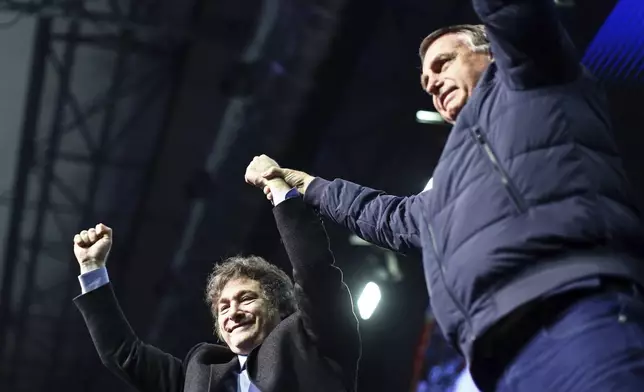 Argentina's President Javier Milei, left, raises his fits with Brazilian former President Jair Bolsonaro during CPAC Brasil 2024, a conservative event, in Balneario Camboriu, Santa Catarina state, Brazil, Sunday, July 7, 2024. (AP Photo/Heuler Andrey)