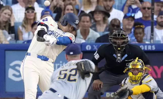 Los Angeles Dodgers' Shohei Ohtani, left, hits a solo home run as Milwaukee Brewers relief pitcher Bryan Hudson, second from left, and catcher William Contreras watch along with home plate umpire Edwin Moscoso during the eighth inning of a baseball game Saturday, July 6, 2024, in Los Angeles. (AP Photo/Mark J. Terrill)