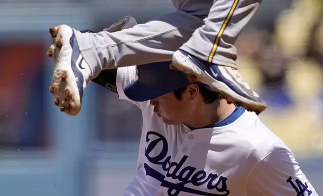 Los Angeles Dodgers' Shohei Ohtani, below, slides into second in an attempt to steal as Milwaukee Brewers second baseman Brice Turang jumps over him during the third inning of a baseball game Sunday, July 7, 2024, in Los Angeles. Shohei Ohtani was called back to first on the play after batter Will Smith interfered with the catcher. (AP Photo/Mark J. Terrill)