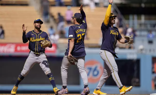 Milwaukee Brewers' Blake Perkins, left, celebrates with Willy Adames, center, and Garrett Mitchell after the Brewers defeated the Los Angeles Dodgers 9-2 in a baseball game Sunday, July 7, 2024, in Los Angeles. (AP Photo/Mark J. Terrill)