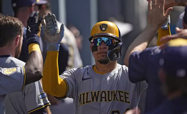 Milwaukee Brewers' William Contreras is congratulated by teammates in the dugout after scoring on a single by Willy Adames during the first inning of a baseball game against the Los Angeles Dodgers Saturday, July 6, 2024, in Los Angeles. (AP Photo/Mark J. Terrill)