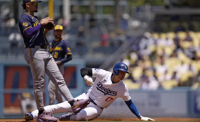 Los Angeles Dodgers' Shohei Ohtani, right, steals second as Milwaukee Brewers shortstop Willy Adames stands by during the third inning of a baseball game Sunday, July 7, 2024, in Los Angeles. (AP Photo/Mark J. Terrill)