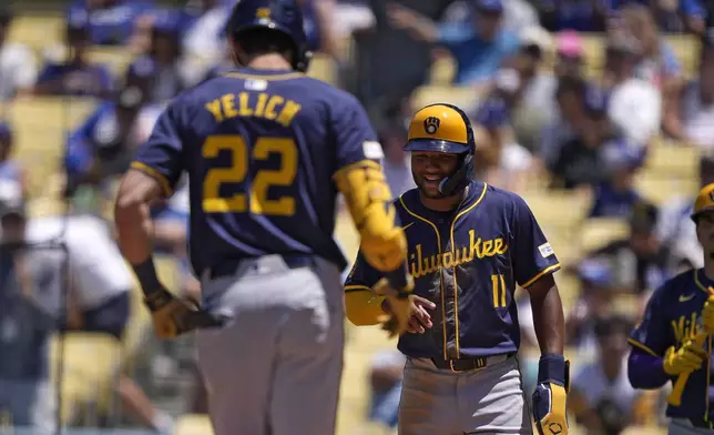 Milwaukee Brewers' Jackson Chourio, right, waits to congratulate Christian Yelich after Yelich hit a two-run home run during the fourth inning of a baseball game against the Los Angeles Dodgers Sunday, July 7, 2024, in Los Angeles. (AP Photo/Mark J. Terrill)