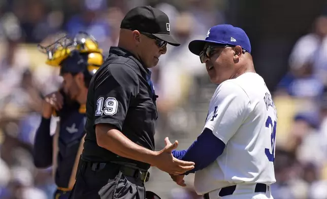 Los Angeles Dodgers manager Dave Roberts, has a discussion with home plate umpire Vic Carapazza after Will Smith was called out for interference with the catcher during the third inning of a baseball game against the Milwaukee Brewers Sunday, July 7, 2024, in Los Angeles. (AP Photo/Mark J. Terrill)