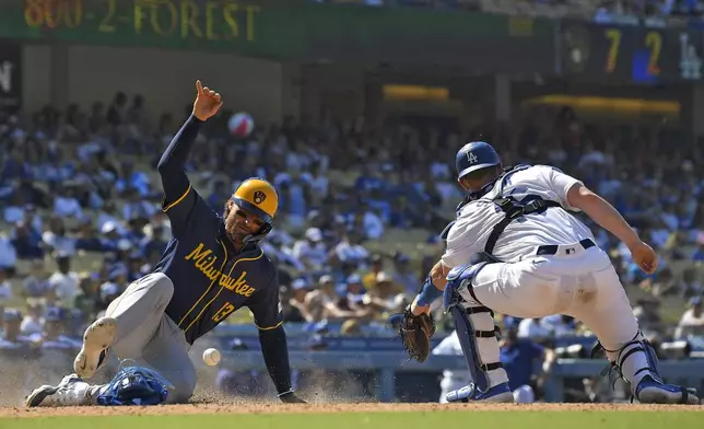 Milwaukee Brewers' Eric Haase, left, scores on a double by Christian Yelich as Los Angeles Dodgers catcher Will Smith misses the throw during the ninth inning of a baseball game Sunday, July 7, 2024, in Los Angeles. (AP Photo/Mark J. Terrill)