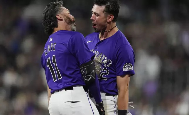 Colorado Rockies' Nolan Jones, right, congratulates Jake Cave, left, after Cave's walkoff RBI single off Milwaukee Brewers relief pitcher Joel Payamps in the 10th inning of a baseball game Monday, July 1, 2024, in Denver. (AP Photo/David Zalubowski)