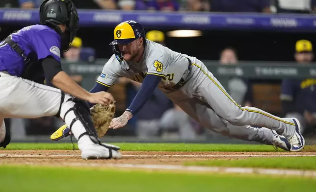 Colorado Rockies catcher Jacob Stallings, left, turns to tag out Milwaukee Brewers' Brice Turang as he tries to score on a single hit by Willy Adames to end the top of the seventh inning of a baseball game Tuesday, July 2, 2024, in Denver. (AP Photo/David Zalubowski)