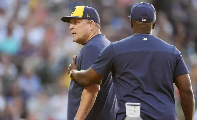 Milwaukee Brewers associate manager Rickie Weeks Jr., right, guides manager Pat Murphy, left, to the clubhouse after Murphy was ejected for arguing a call by home plate umpire Brennan Miller in the fifth inning of a baseball game against the Colorado Rockies, Monday, July 1, 2024, in Denver. (AP Photo/David Zalubowski)