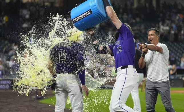 Colorado Rockies' Charlie Blackmon, center, douses Jake Cave, left, after Cave's walkoff RBI single off Milwaukee Brewers relief pitcher Joel Payamps in the 10th inning of a baseball game Monday, July 1, 2024, in Denver. (AP Photo/David Zalubowski)