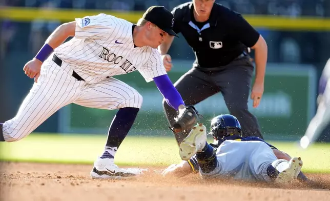 Colorado Rockies shortstop Aaron Schunk, left, applies a late tag as Milwaukee Brewers' Sal Frelick advances from first to second base on a passed ball as second base umpire Brennan Miller, back, looks on in the second inning of a baseball game Wednesday, July 3, 2024, in Denver. (AP Photo/David Zalubowski)