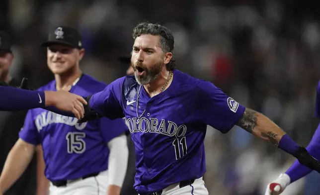 Colorado Rockies' Jake Cave (11) celebrates after hitting a walkoff RBI single off Milwaukee Brewers relief pitcher Joel Payamps in the 10th inning of a baseball game Monday, July 1, 2024, in Denver. (AP Photo/David Zalubowski)