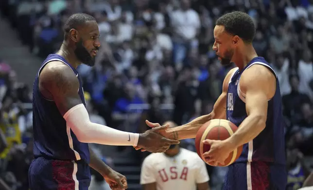 United States' forward LeBron James, left and United States' guard Stephen Curry shake hands during an exhibition basketball game between the United States and South Sudan, at the o2 Arena in London, Saturday, July 20, 2024. (AP Photo/Kin Cheung)