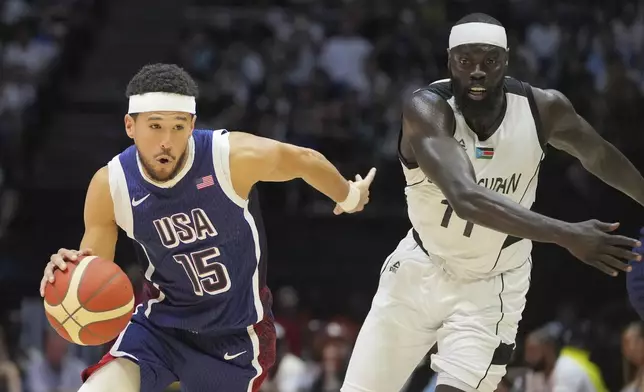 United States' guard Devin Booker, left, takes the ball forward as South Sudan's guard Marial Shayok follows during an exhibition basketball game between the United States and South Sudan, at the o2 Arena in London, Saturday, July 20, 2024. (AP Photo/Kin Cheung)