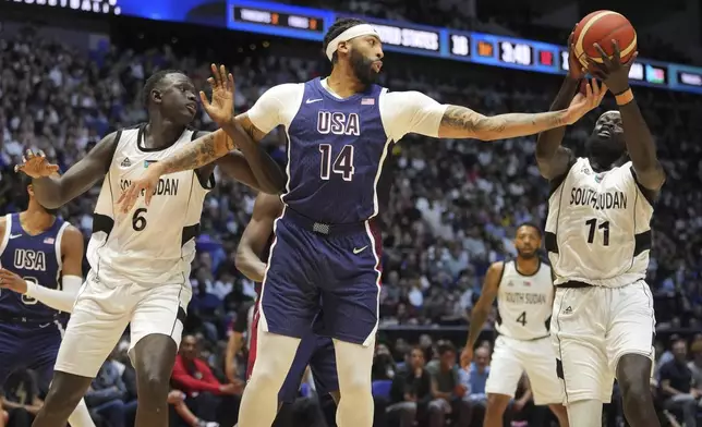 United States' forward Anthony Davis, center, reaches for the ball with South Sudan's guard Marial Shayok, right, as South Sudan's center Khaman Maluach follows the action during an exhibition basketball game between United States and South Sudan, at the o2 Arena in London, Saturday, July 20, 2024. (AP Photo/Kin Cheung)