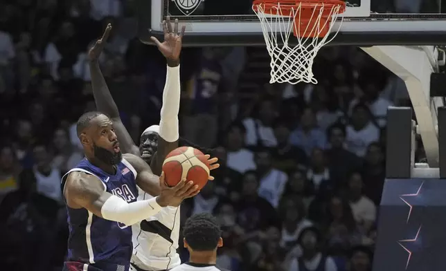 United States' forward LeBron James, left attempts to scores as South Sudan's forward Wenyen Gabriel tries to block during an exhibition basketball game between the United States and South Sudan, at the o2 Arena in London, Saturday, July 20, 2024. (AP Photo/Kin Cheung)