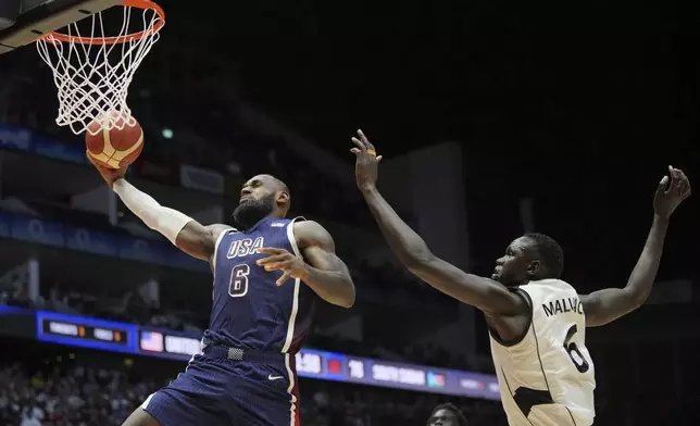 United States' forward LeBron James scores as South Sudan's center Khaman Maluach attempted top defend during an exhibition basketball game between the United States and South Sudan, at the o2 Arena in London, Saturday, July 20, 2024. (AP Photo/Kin Cheung)