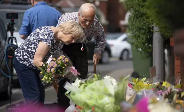 An elderly couple leaves a floral tribute near the scene in Hart Street, where three children died and eight were injured in a knife attack during a Taylor Swift event at a dance school on Monday, in Southport, England, Tuesday, July 30, 2024. (James Speakman/PA via AP)