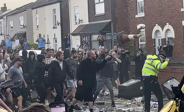 An unruly crowd clash with police, Tuesday, July 30, 2024, in Southport, northwest England, near where three girls were stabbed to death in a dance class the day before. The violence erupted shortly after a peaceful vigil was attended by hundreds in the center of Southport to mourn the 13 victims of the stabbings, including seven still in critical condition. (Richard McCarthy/PA via AP)