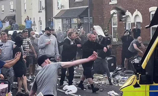 An unruly crowd clash with police, Tuesday, July 30, 2024, in Southport, northwest England, near where three girls were stabbed to death in a dance class the day before. The violence erupted shortly after a peaceful vigil was attended by hundreds in the center of Southport to mourn the 13 victims of the stabbings, including seven still in critical condition. (Richard McCarthy/PA via AP)