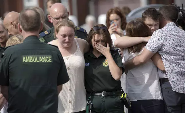 Emergency personnel comfort members of the public near the scene in Hart Street, where three children died and eight were injured in a knife attack during a Taylor Swift event at a dance school on Monday, in Southport, England, Tuesday, July 30, 2024. (James Speakman/PA via AP)