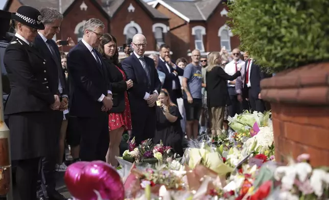 British Prime Minister Keir Starmer, third from left, observes floral tributes near the scene in Hart Street, where three children died and eight were injured in a knife attack during a Taylor Swift event at a dance school on Monday, in Southport, England, Tuesday, July 30, 2024. (James Speakman/PA via AP)