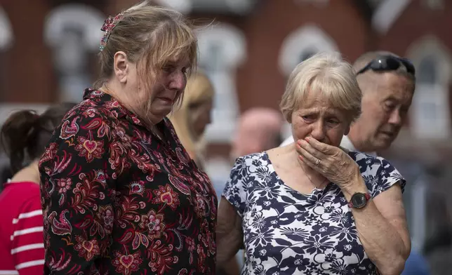 Members of the public look at the floral tributes near the scene in Hart Street, in Southport, England, Tuesday, July 30, 2024, where three children died and eight were injured in a knife attack during a Taylor Swift event at a dance school on Monday. (James Speakman/PA via AP)