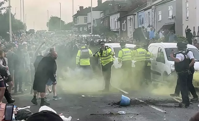 An unruly crowd clash with police, Tuesday, July 30, 2024, in Southport, northwest England, near where three girls were stabbed to death in a dance class the day before. The violence erupted shortly after a peaceful vigil was attended by hundreds in the center of Southport to mourn the 13 victims of the stabbings, including seven still in critical condition. (Richard McCarthy/PA via AP)