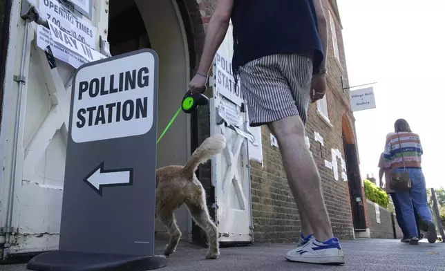 People walk into a temporary polling station at Wimbledon Village, London, Thursday, July 4, 2024. Voters in the U.K. are casting their ballots in a national election to choose the 650 lawmakers who will sit in Parliament for the next five years. (AP Photo/Mark Baker)