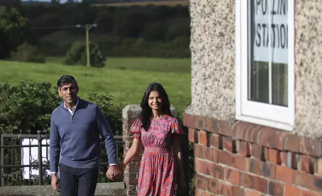 Britain's Prime Minister Rishi Sunak and his wife Akshata Murty walk to a polling station to vote near Richmond, North Yorkshire, England, Thursday, July 4, 2024. Britain goes to the polls Thursday after Prime Minister Rishi Sunak called a general election. (AP Photo/Scott Heppell )
