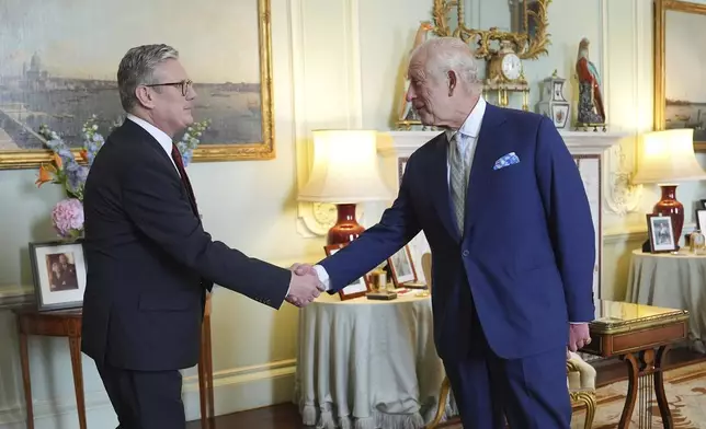 Britain's King Charles III, right, shakes hands with Keir Starmer where he invited the Labour Party leader to become prime minister and to form a new government, following the landslide general election victory for the Labour Party, in London, Friday, July 5, 2024. (Yui Mok, Pool Photo via AP)