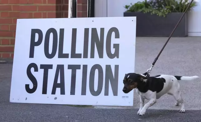 A voter leaves a polling station after casting his vote with his dog in Kingston, London, Thursday, July 4, 2024. Britain goes to the polls Thursday after Prime Minister Rishi Sunak called a general election. (AP Photo/Kin Cheung)