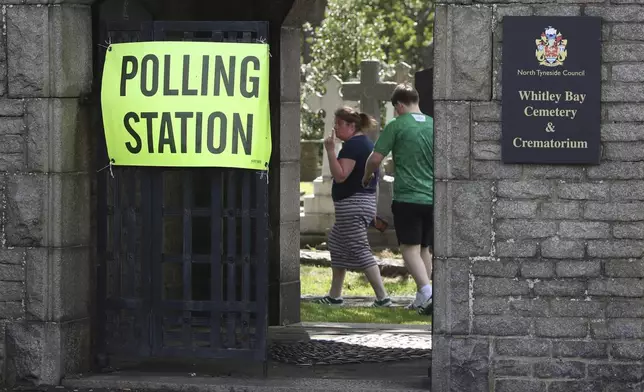 Voters arrive to cast their votes at Whitley Bay cemetery where there is polling station inside, in Whitley Bay, England, Thursday, July 4, 2024. Britain goes to the polls Thursday after Prime Minister Rishi Sunak called a general election. (AP Photo/Scott Heppell)