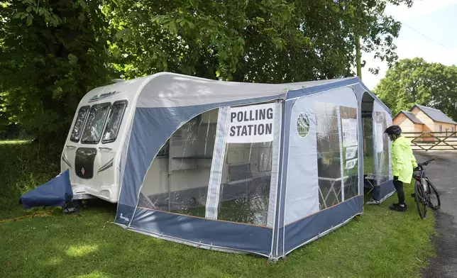 A cyclist arrives to cast her vote in a caravan used as a polling station in the 2024 General Election, in Carlton, England, Thursday July 4, 2024. (Joe Giddens/PA via AP)